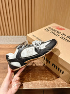 Black and white unisex sneakers held up, showing side panels and laces