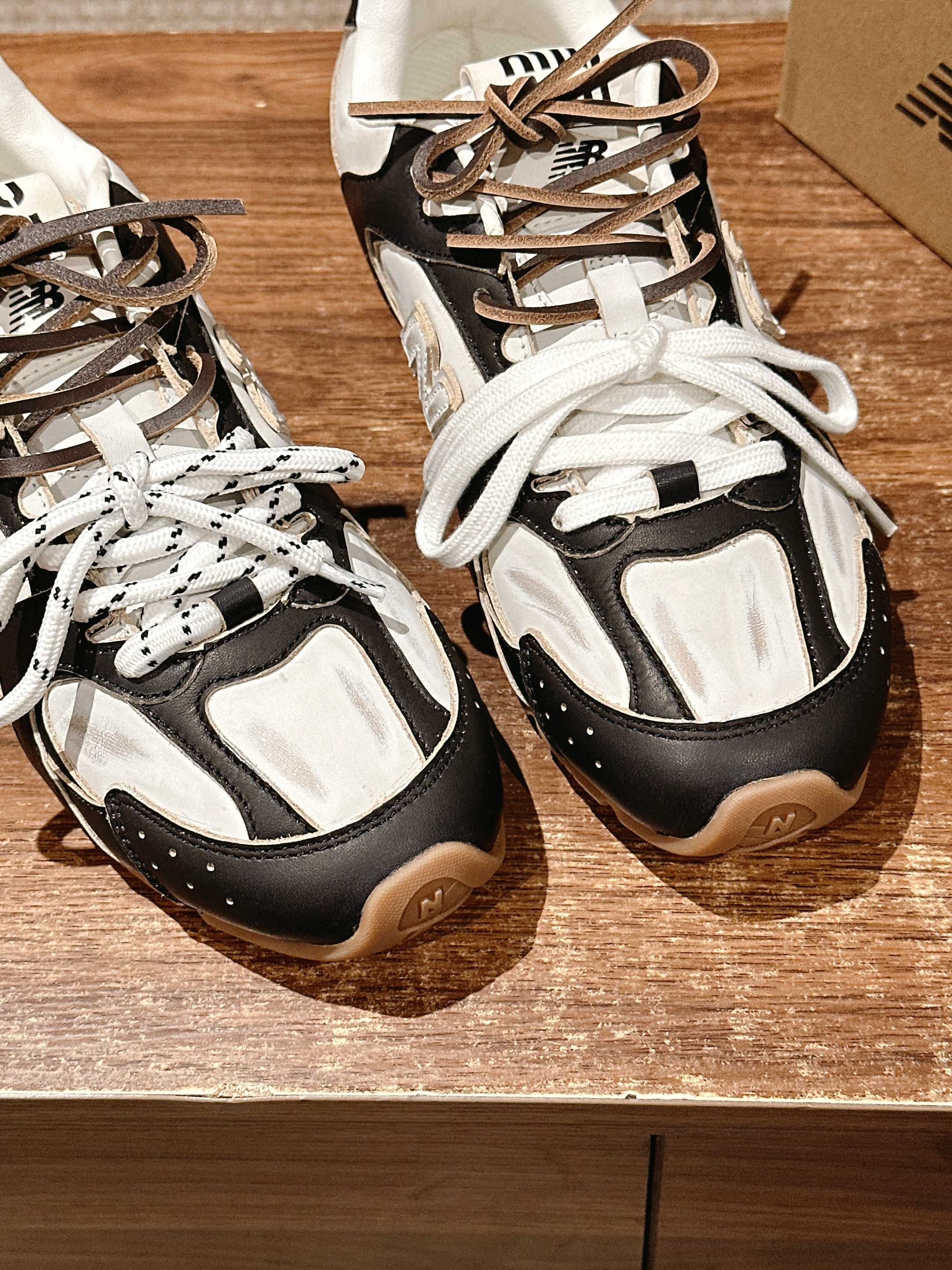 Black and white unisex sneakers on a surface, both toe areas and laces visible
