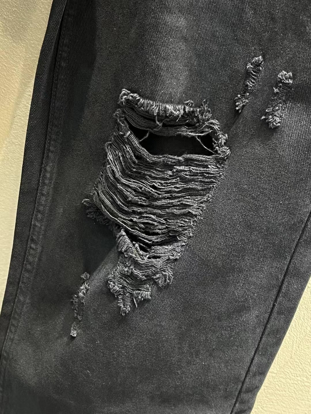 Balenciaga dark denim jeans close-up of layered ripped fabric on the leg