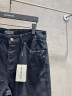 Balenciaga dark denim jeans with large rips at the legs and button fly