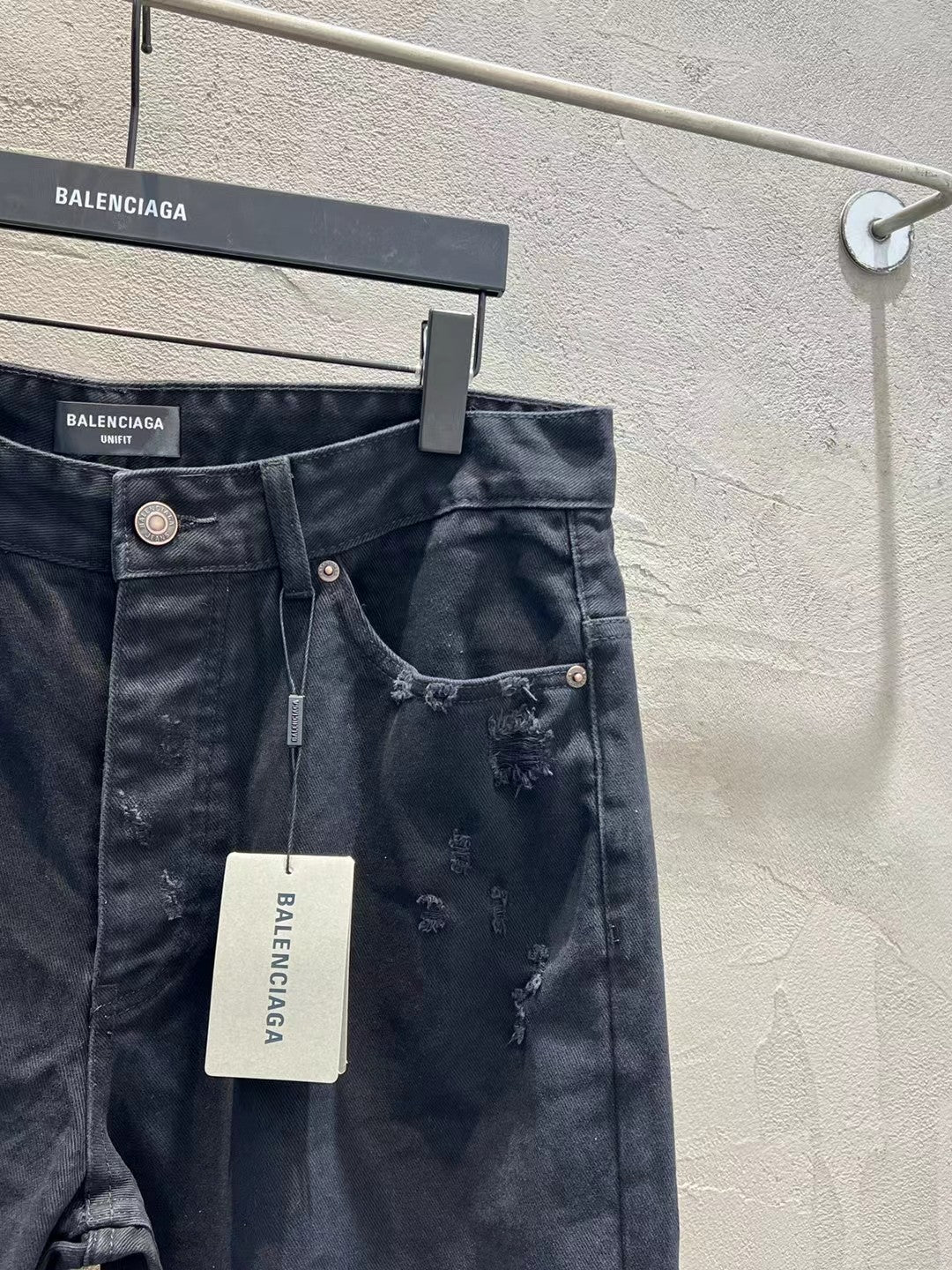 Balenciaga dark denim jeans with large rips at the legs and button fly