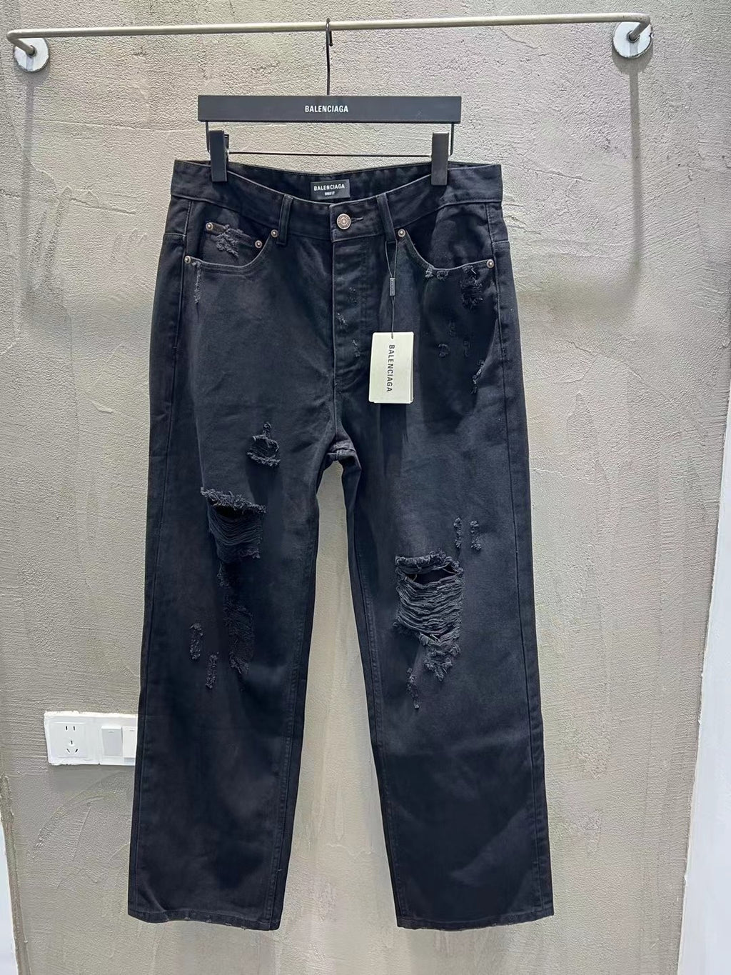 Balenciaga dark denim jeans with ripped knees and front button closure