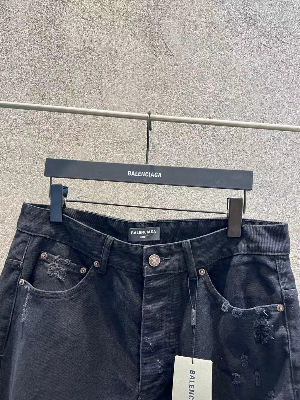 Balenciaga dark denim jeans showing waistband, pockets, and ripped knee detailing