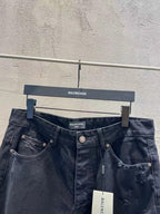 Balenciaga dark denim jeans showing waistband, pockets, and ripped knee detailing