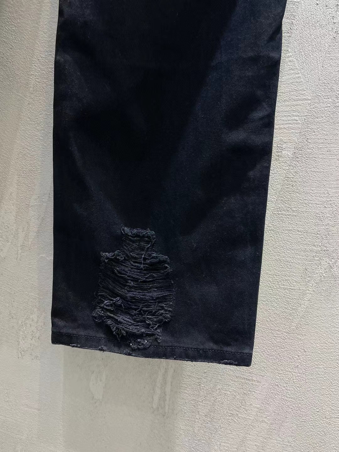 Balenciaga dark denim jeans with heavy frayed rip detail on the leg