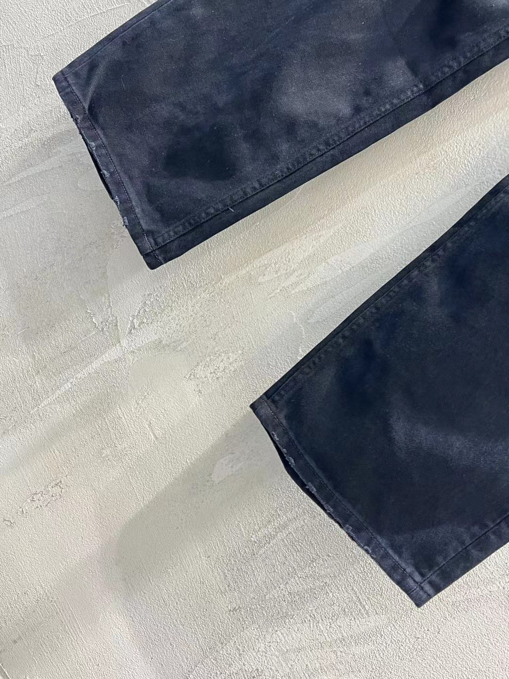 Balenciaga dark denim jeans laid flat, showing stitched hem and leg rips