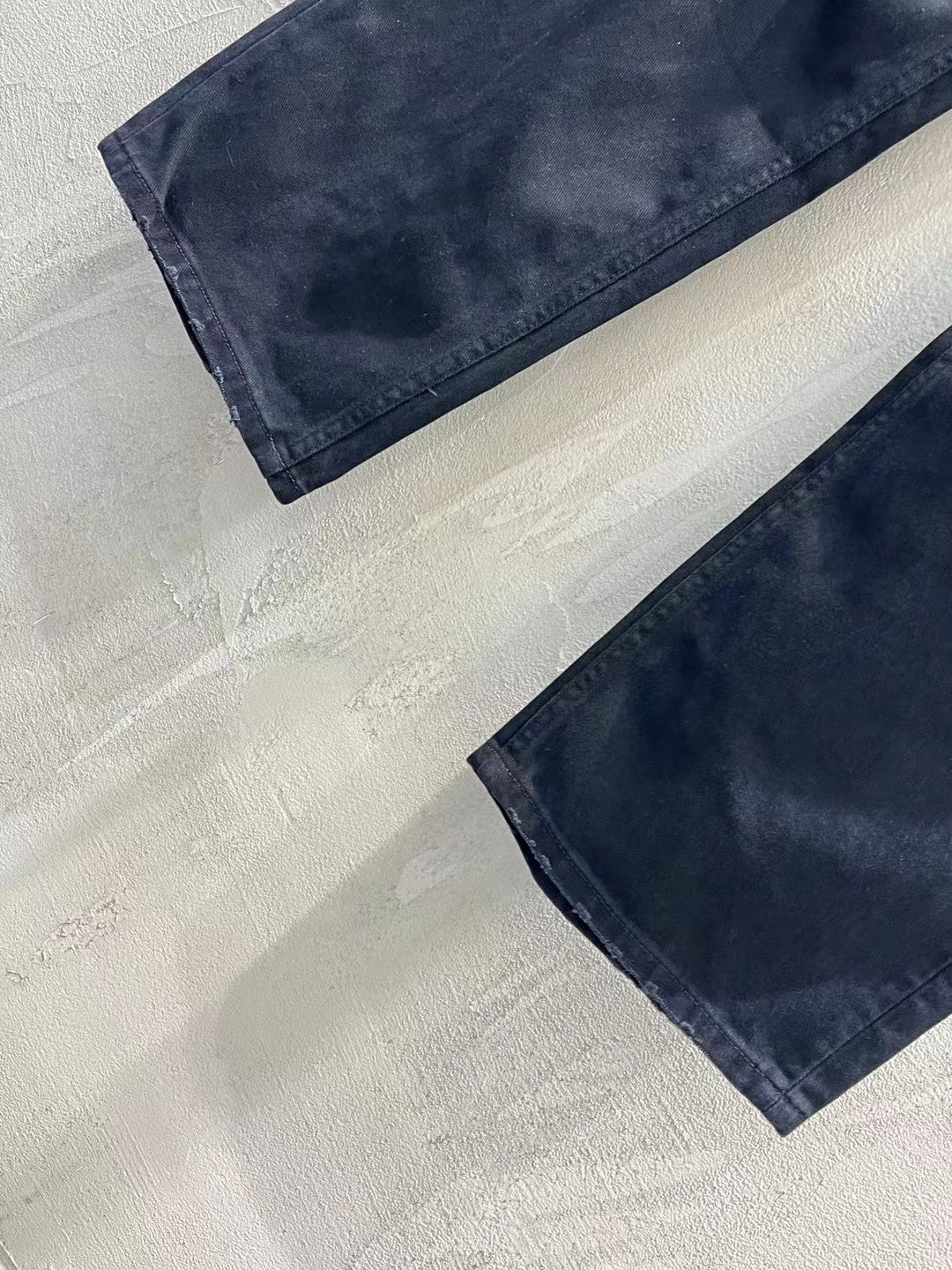 Balenciaga dark denim jeans laid flat, showing stitched hem and leg rips