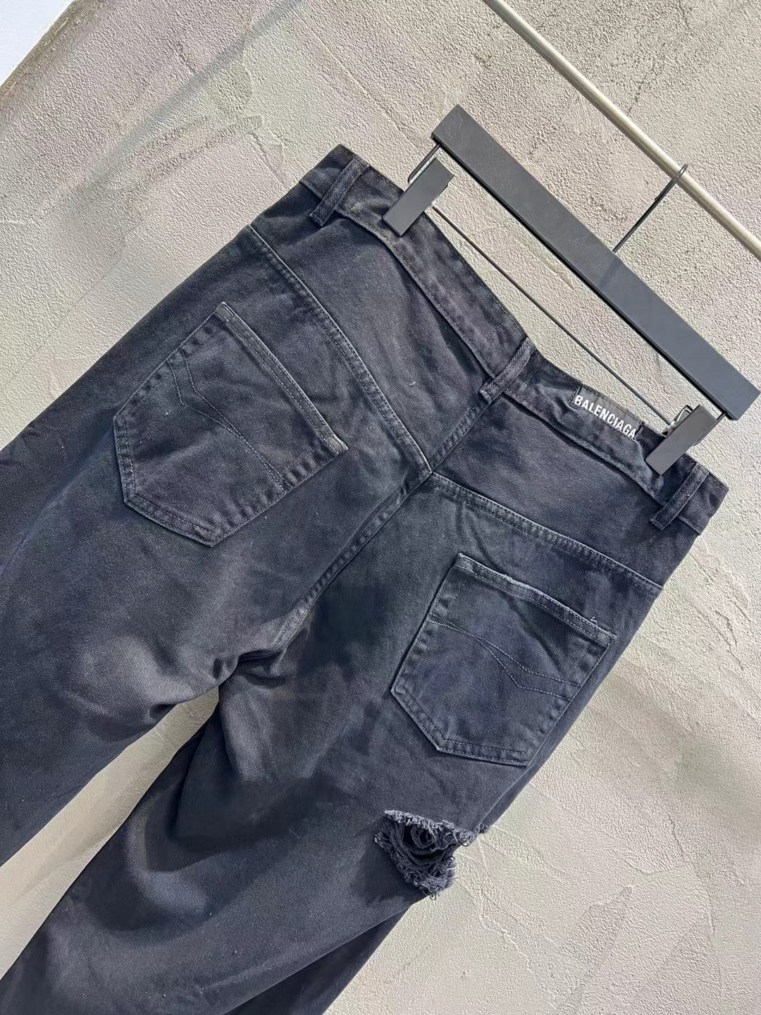 Balenciaga dark denim jeans angled view with front pockets and distressing