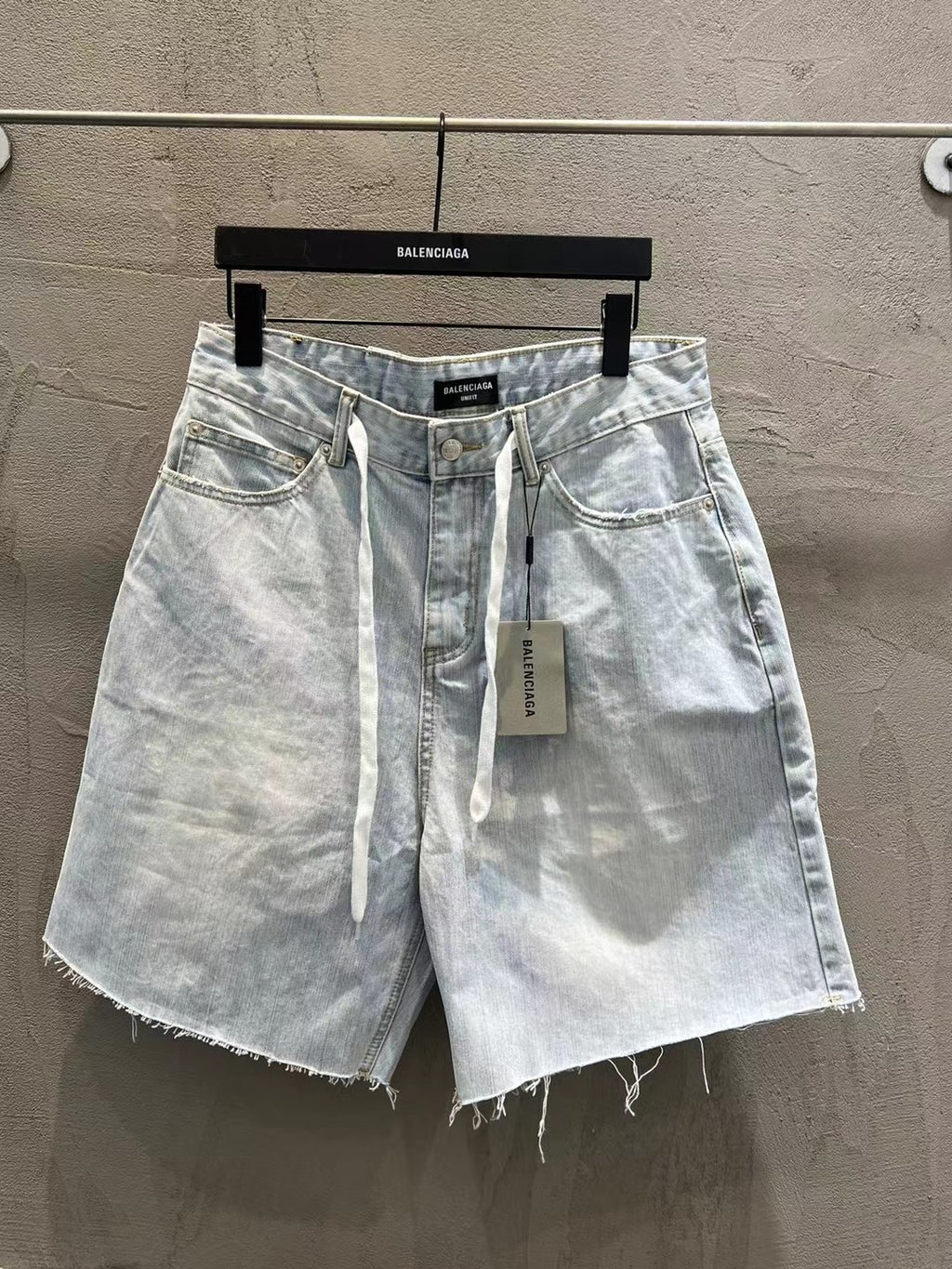 Light-wash denim shorts with drawstring tie, front pockets, and frayed hem