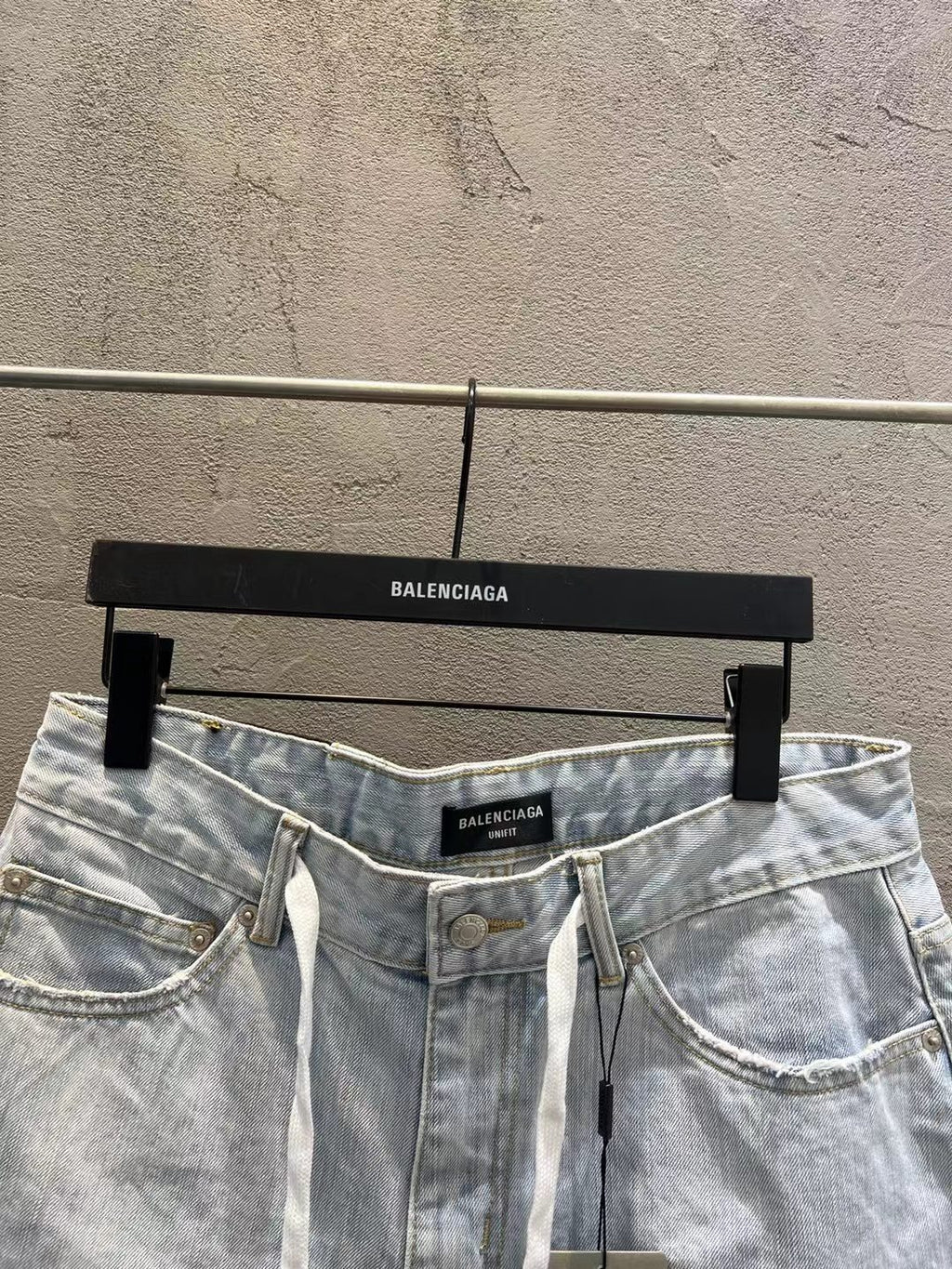 Light-wash denim shorts showing waistband, button closure, and drawstring