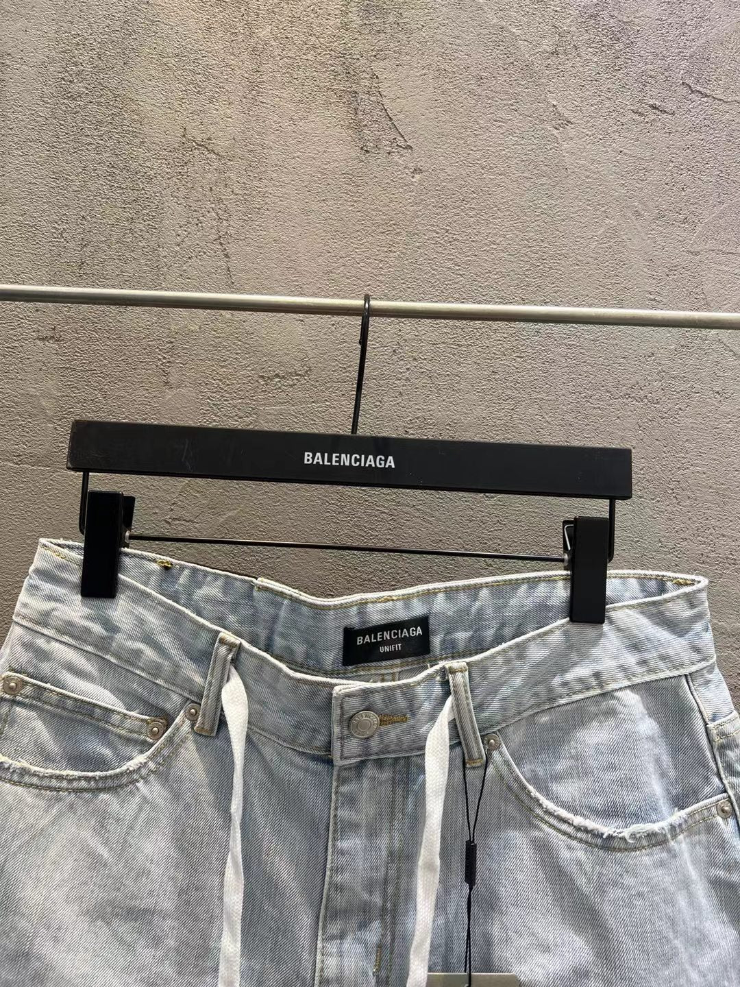 Light-wash denim shorts showing waistband, button closure, and drawstring