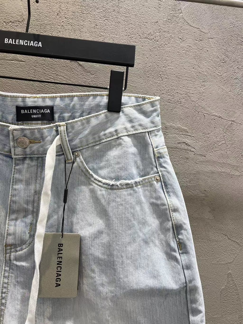 Light-wash denim shorts with curved pocket stitching and hanging drawstring tag