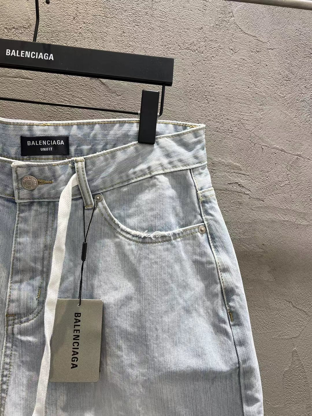 Light-wash denim shorts with curved pocket stitching and hanging drawstring tag