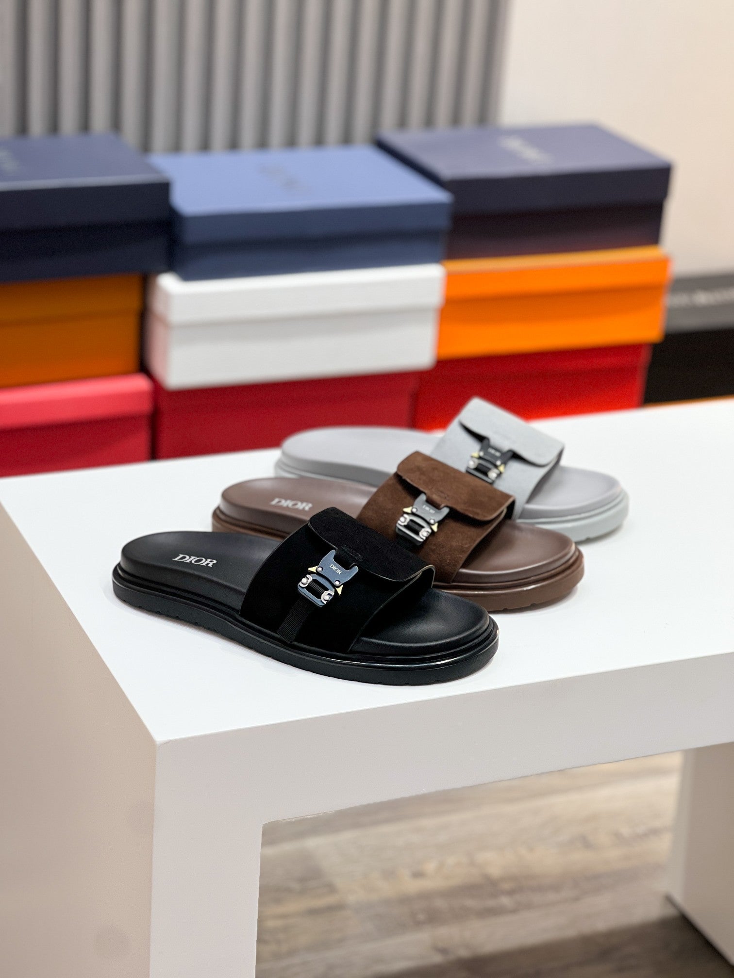 Dior slide sandals in black and brown with metal buckle across the strap