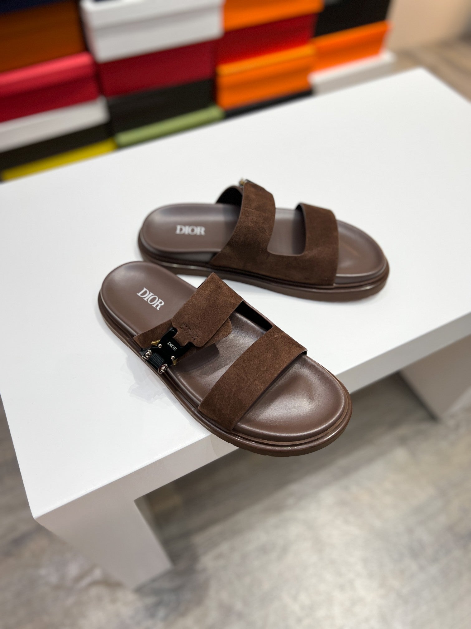 Brown Dior slide sandals, suede strap across the foot with metal buckle