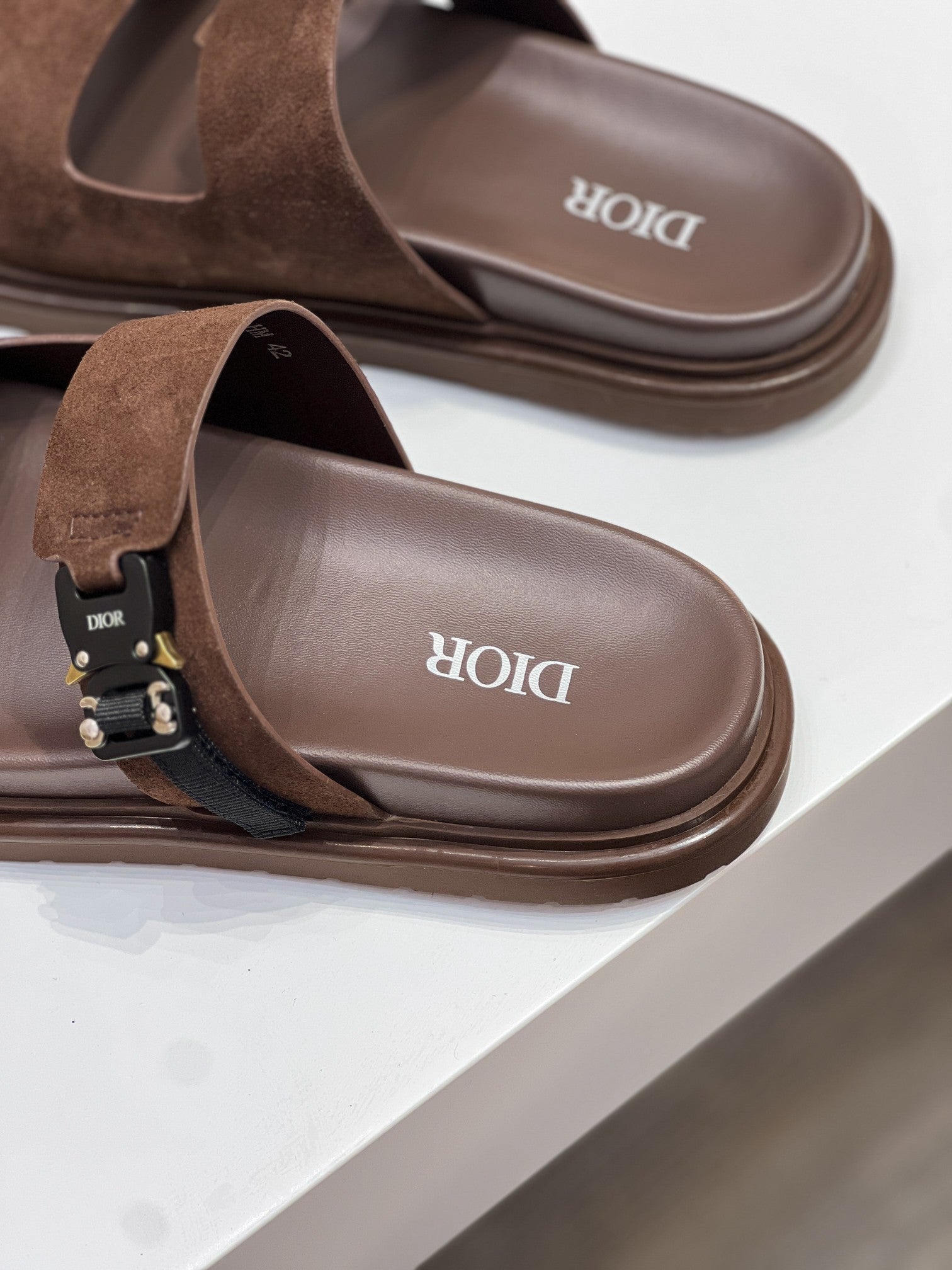 Brown Dior slide sandals with cushioned footbed and molded strap shape
