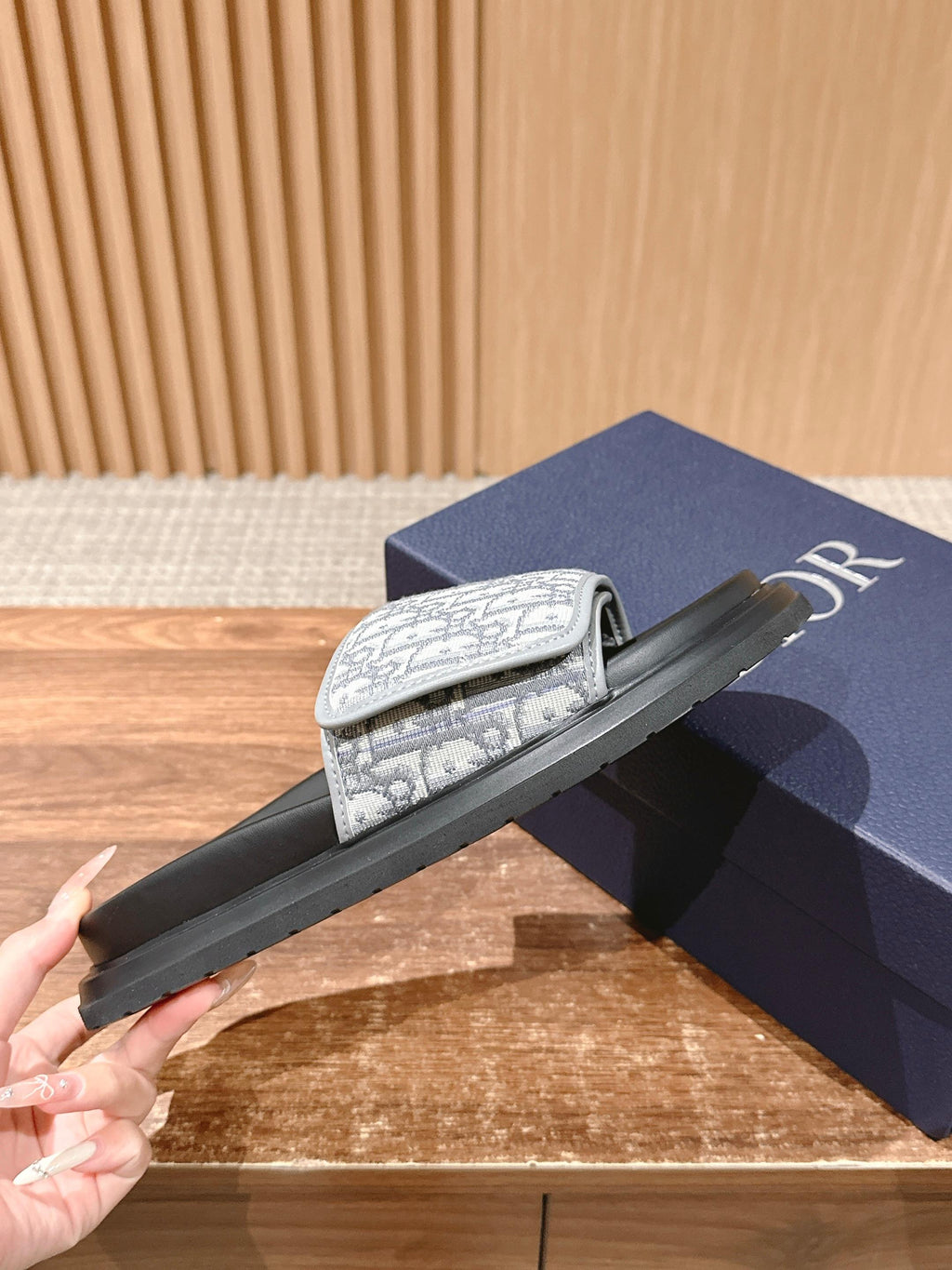 Dior slide sandals held by hand, black sole and white logo-print strap