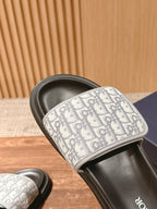 Dior slide sandal close-up on black footbed with white logo-print strap