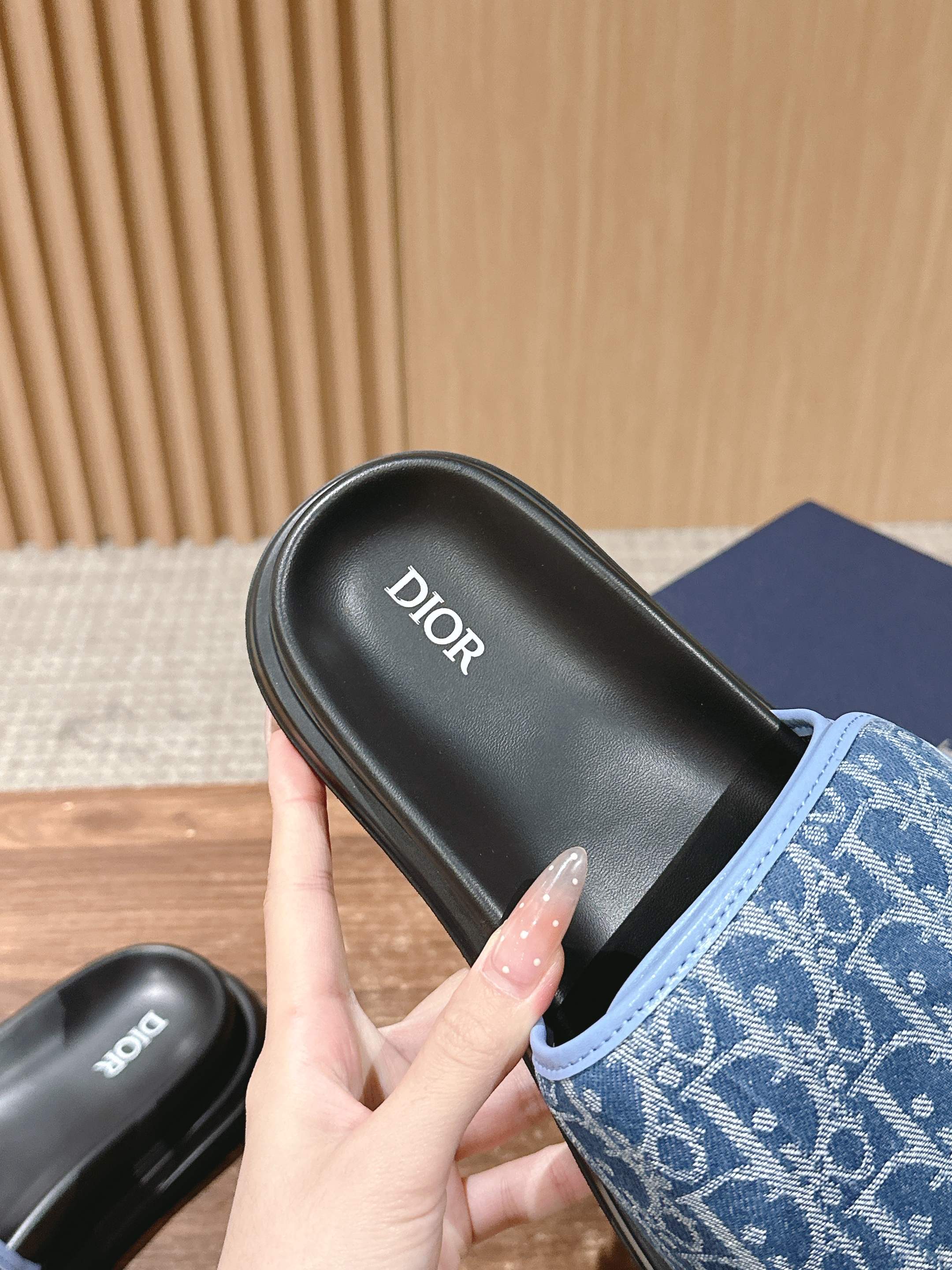 Close-up of Dior slide sandal with blue monogram strap and black footbed