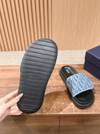 Treaded sole of a black slide sandal next to a blue monogram sandal