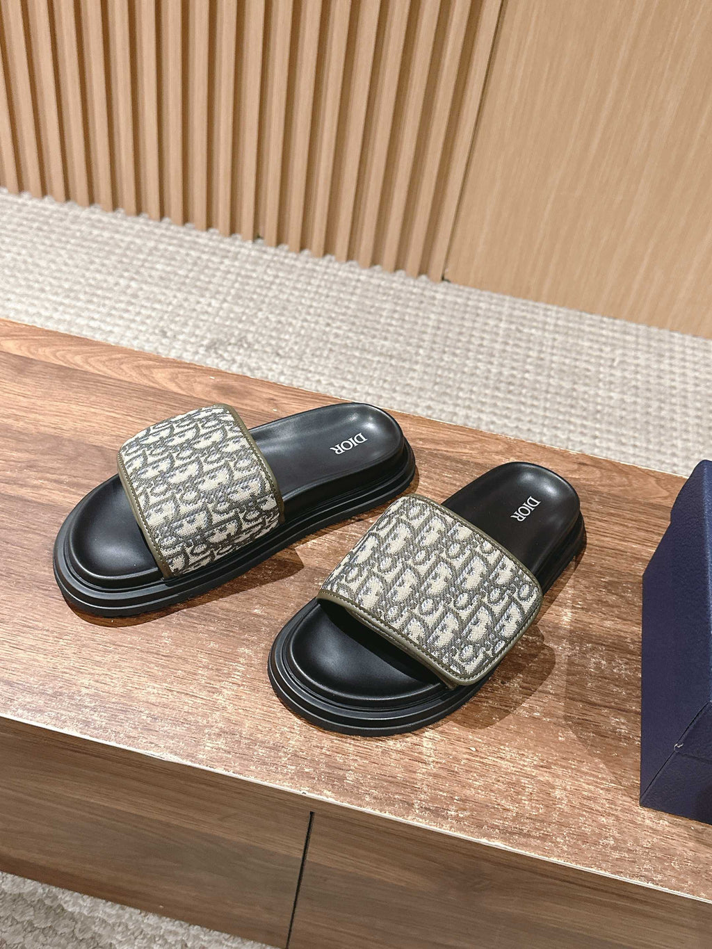 Pair of black slide sandals with beige Dior Oblique logo straps and ribbed outsole
