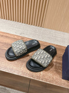 Pair of black slide sandals with beige Dior Oblique logo straps and ribbed outsole