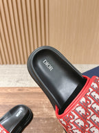 Dior slide sandal close-up of black footbed with Dior text and red strap