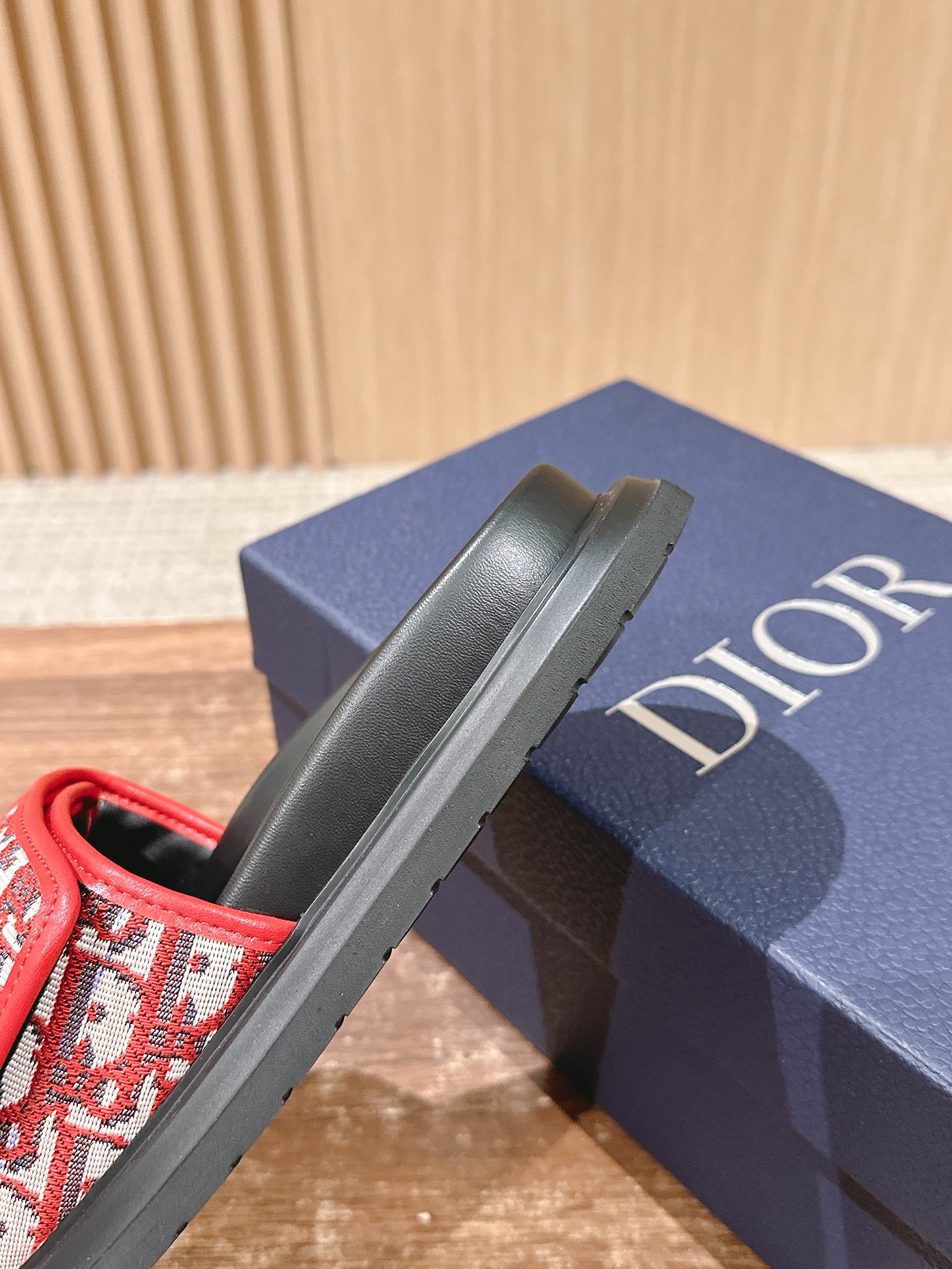 Dior slide sandal side view, red monogram strap on black platform sole