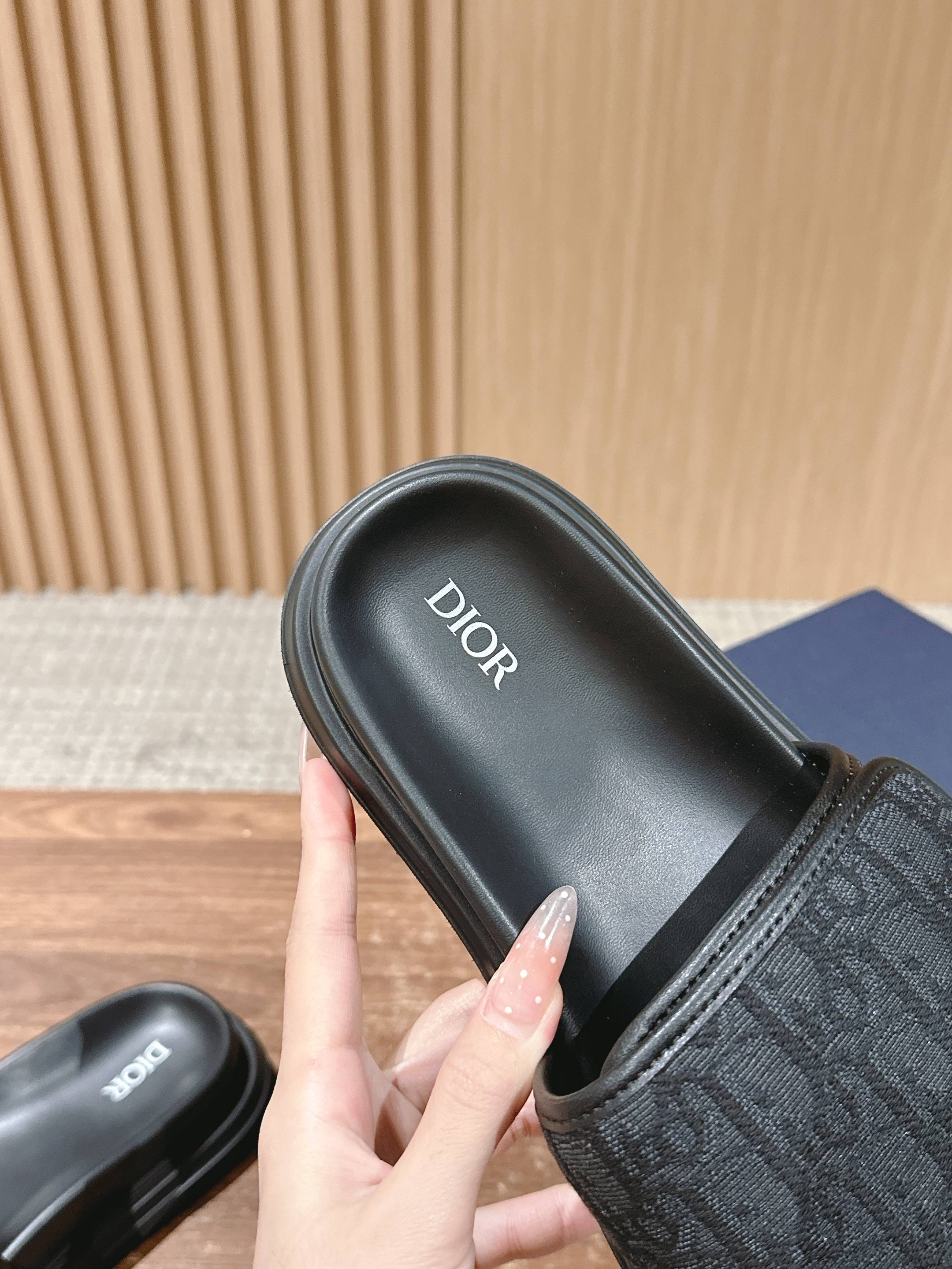 Dior slide sandals with black footbed labeled Dior and logo-pattern strap
