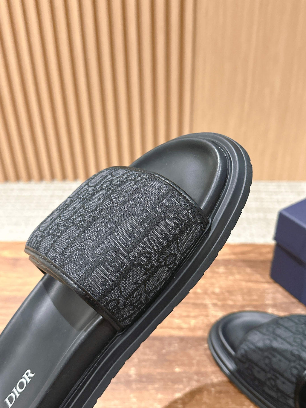 Dior slide sandals close-up of dark logo-pattern strap on black slide