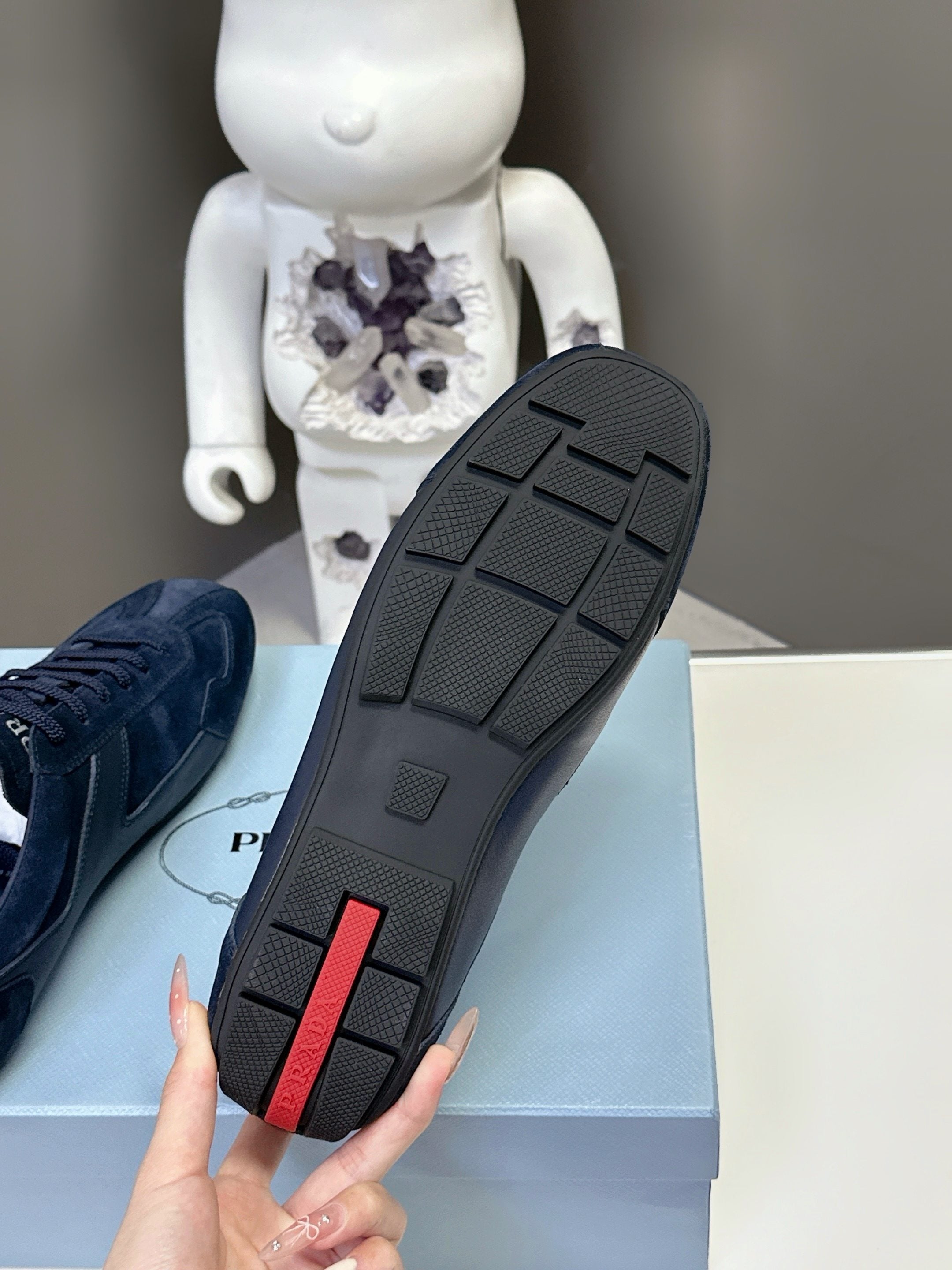 Navy suede sneaker outsole with tread pattern and red vertical heel detail