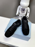 Black Prada unisex sneakers on light blue box, lace-up style with dark rubber sole