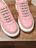 Closeup of pink leather lace-up sneakers with stitched eyelets and white sole