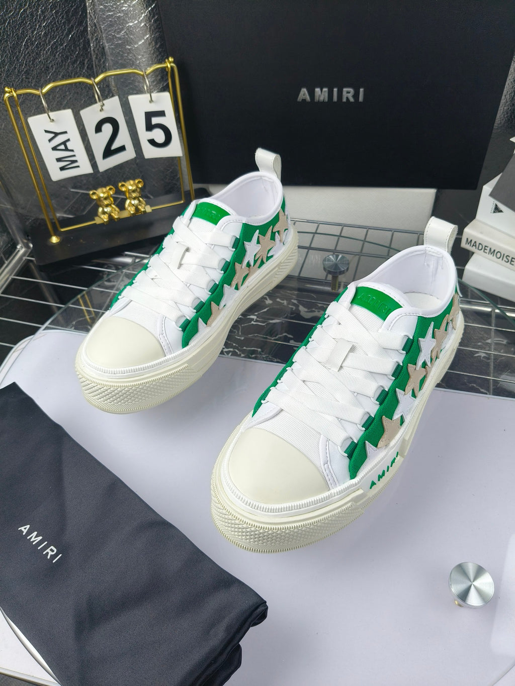 White low-top sneakers with green star motif and white laces, Amiri branding, pair view