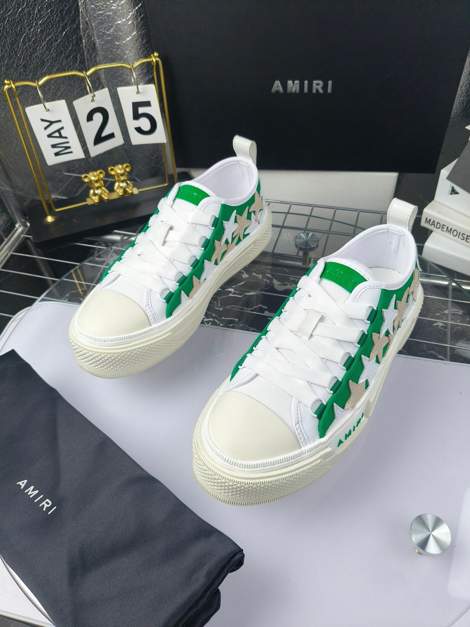 White low-top sneakers with green star motif and white laces, Amiri branding, pair view