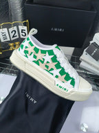 White low-top sneakers with green star pattern and white laces, Amiri branding