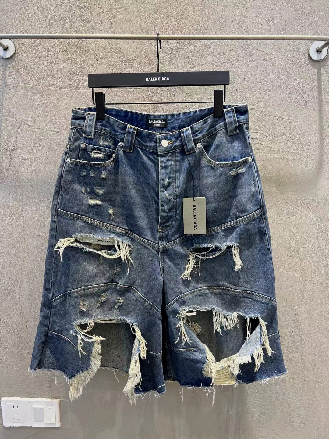 Distressed blue denim shorts with frayed hem, rips, and belt loops