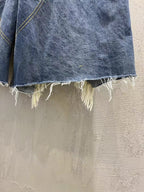 Hem detail of blue denim shorts with raw frayed edge
