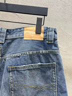 Blue denim shorts detail with tan logo patch at waistband and stitched front pockets