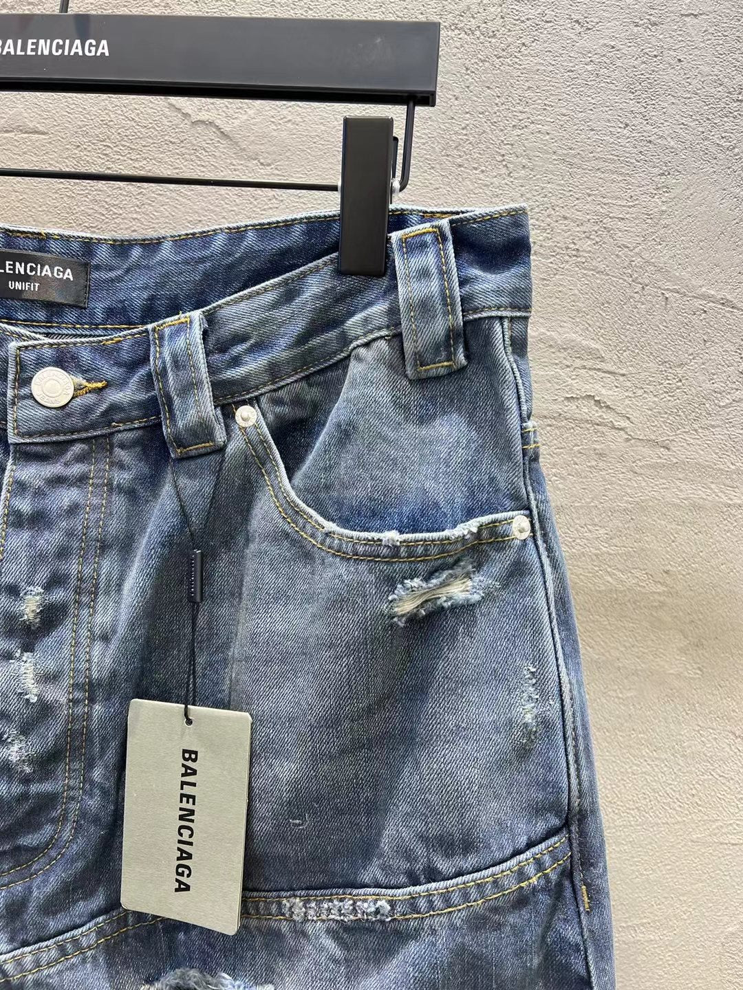 Blue denim shorts front view with belt loops, button closure, and logo hang tag