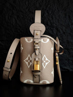 Louis Vuitton monogram bucket bag with brass lock detail and light beige strap hardware