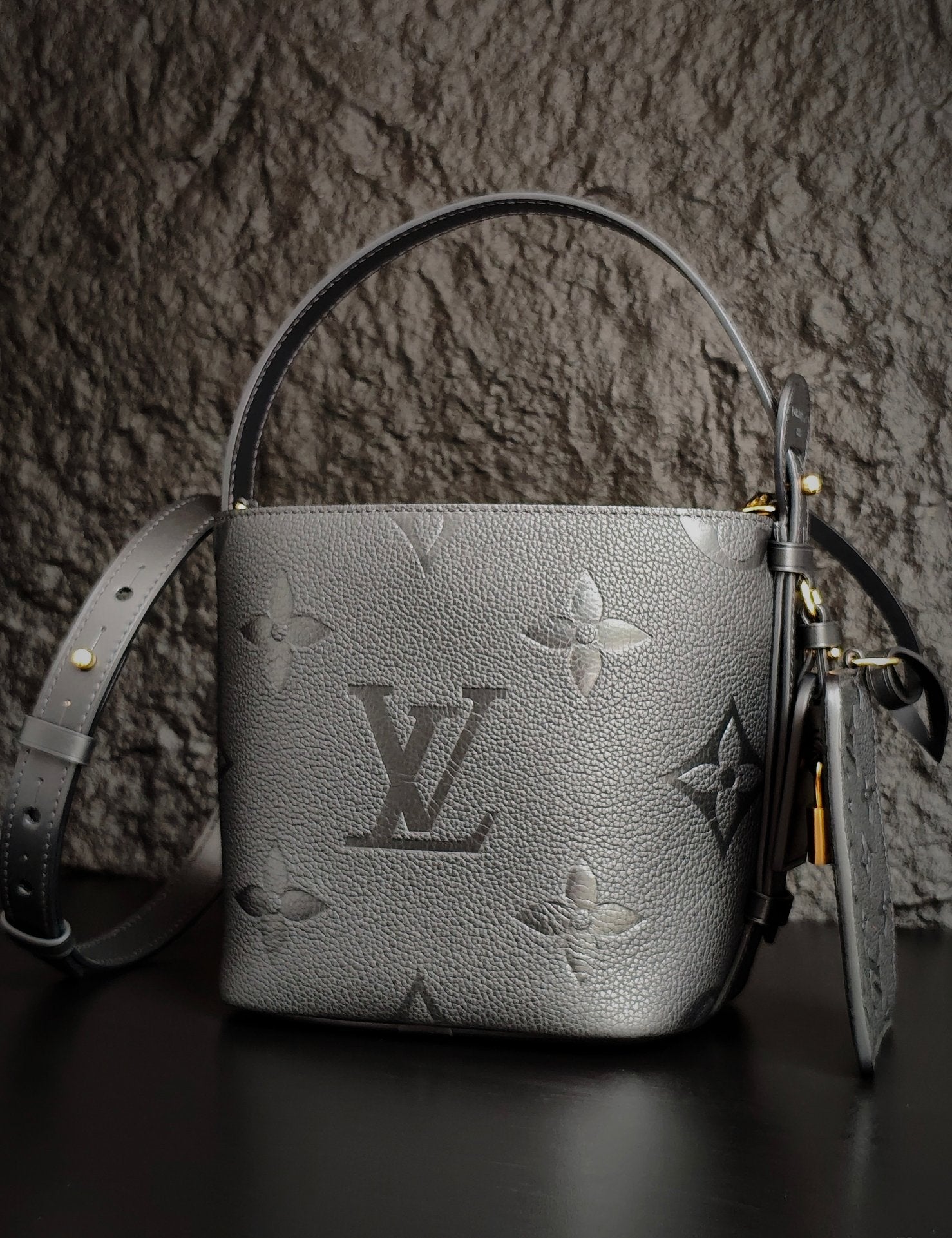 Louis Vuitton monogram bucket bag in gray with curved handle and shoulder strap