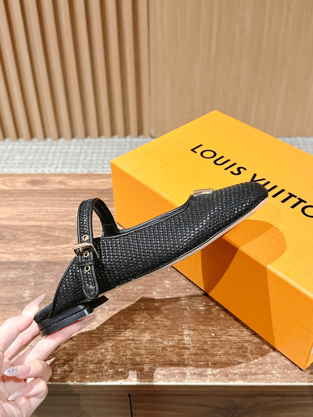 Louis Vuitton unisex black textured flats with gold buckle, held by hand