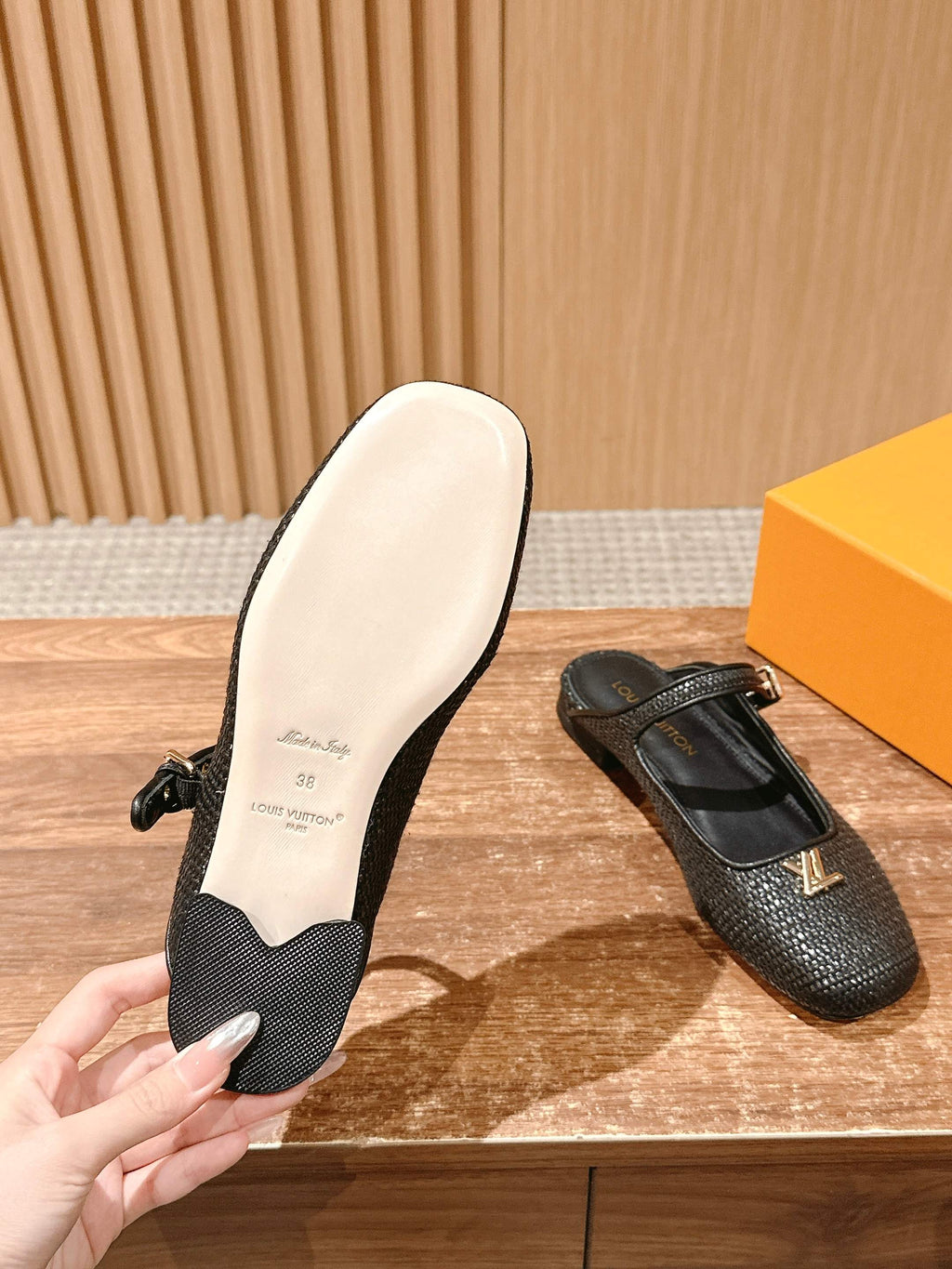 Louis Vuitton unisex black textured flats with light sole, hand holding back shoe