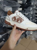 White leather lace-up sneakers with AMIRI logo on side and brown gum sole