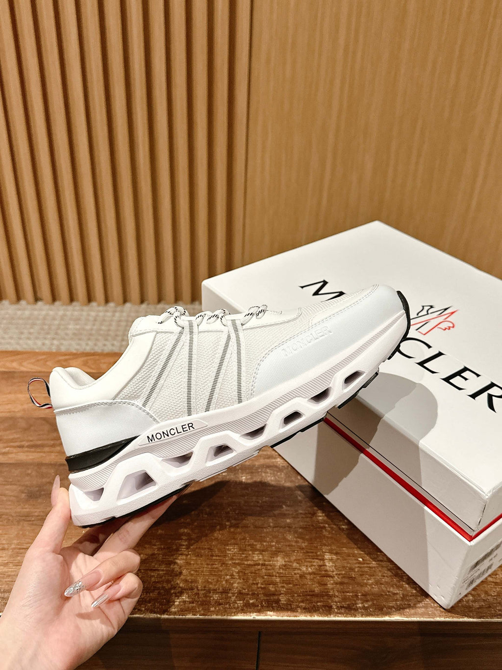 White Moncler knit sneakers with air-cushioned sole cutouts and logo heel tab.