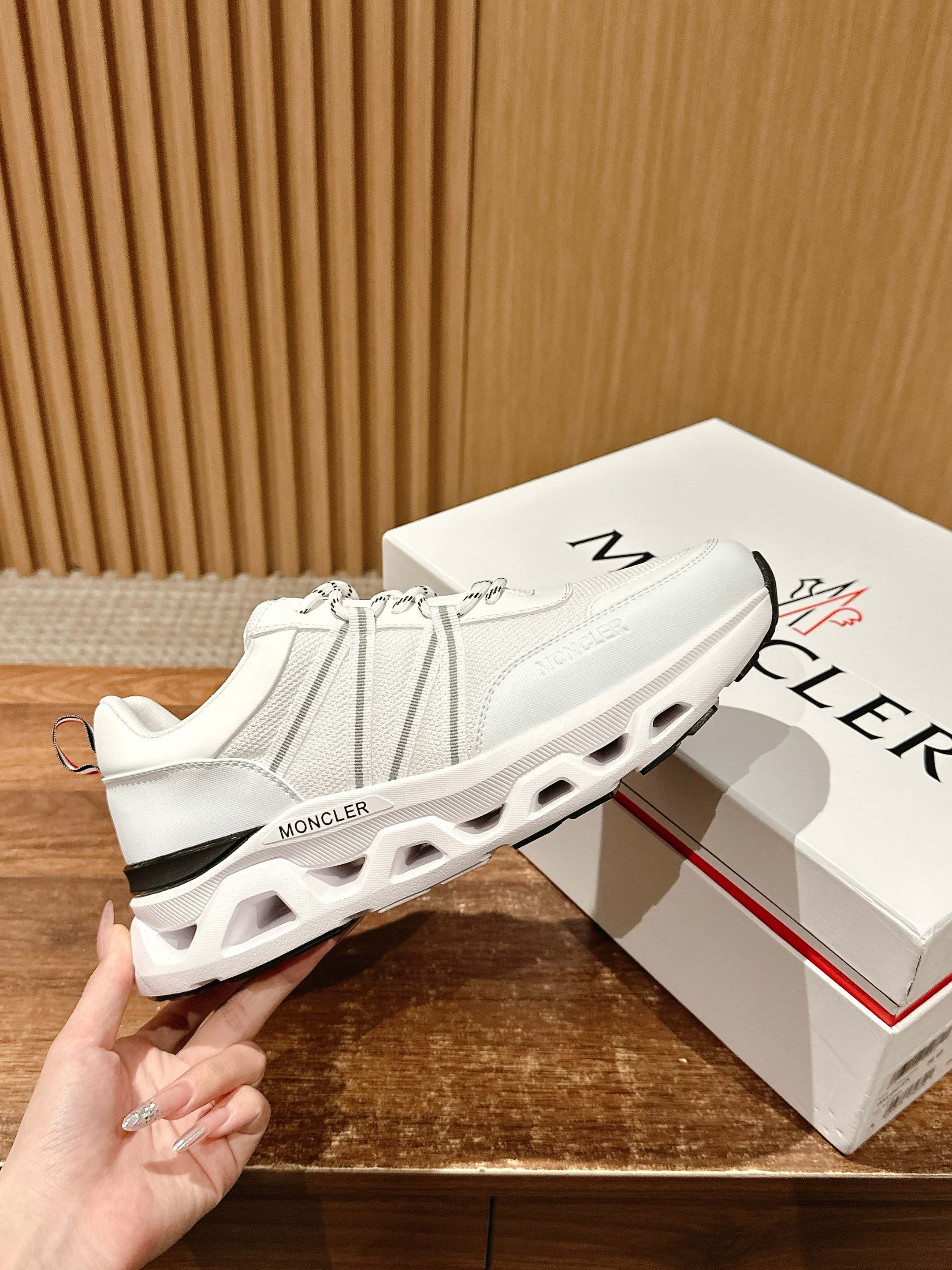 White Moncler knit sneakers with air-cushioned sole cutouts and logo heel tab.