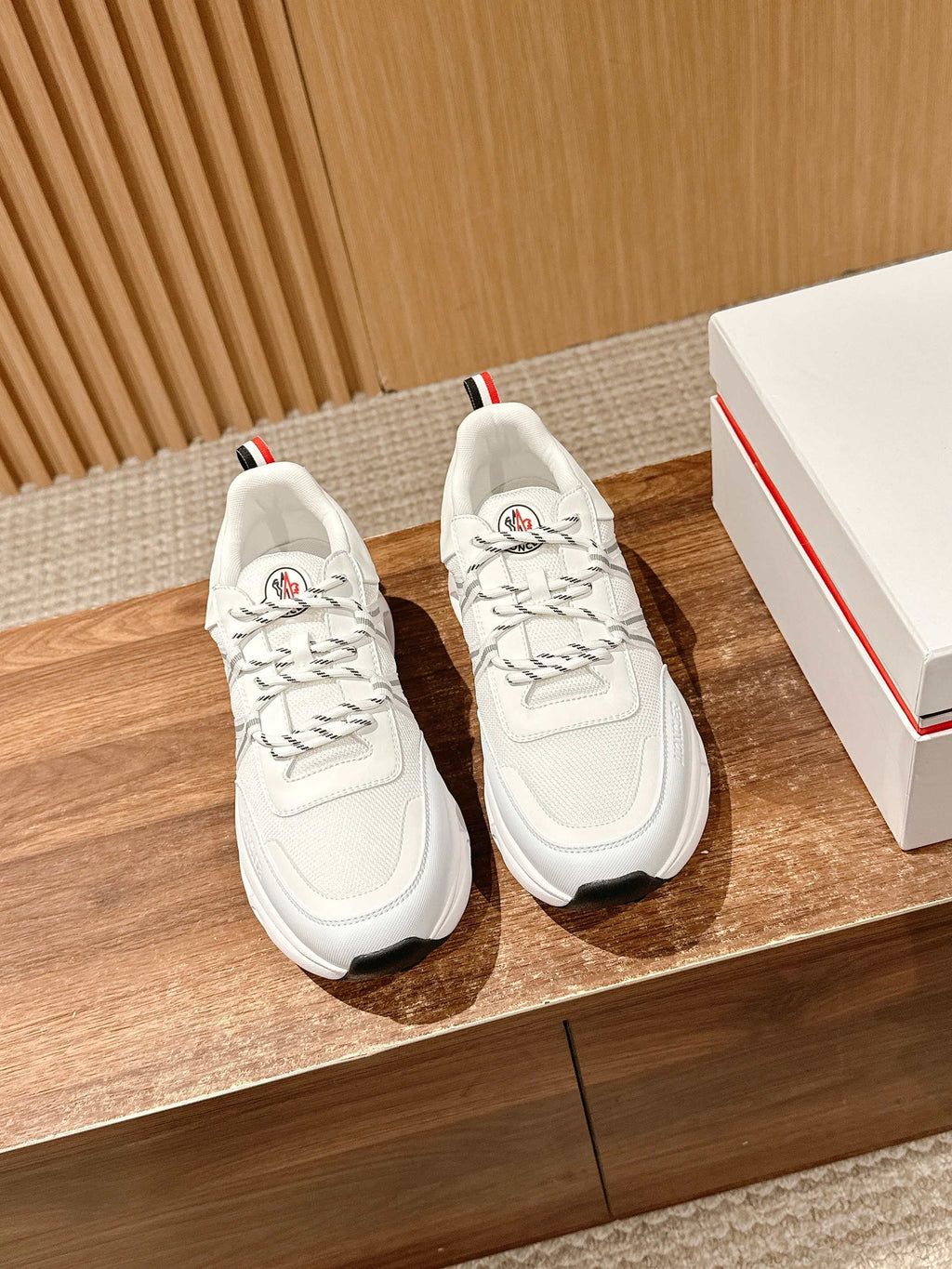 White Moncler low-top sneakers with lace-up front and logo patch on tongue.