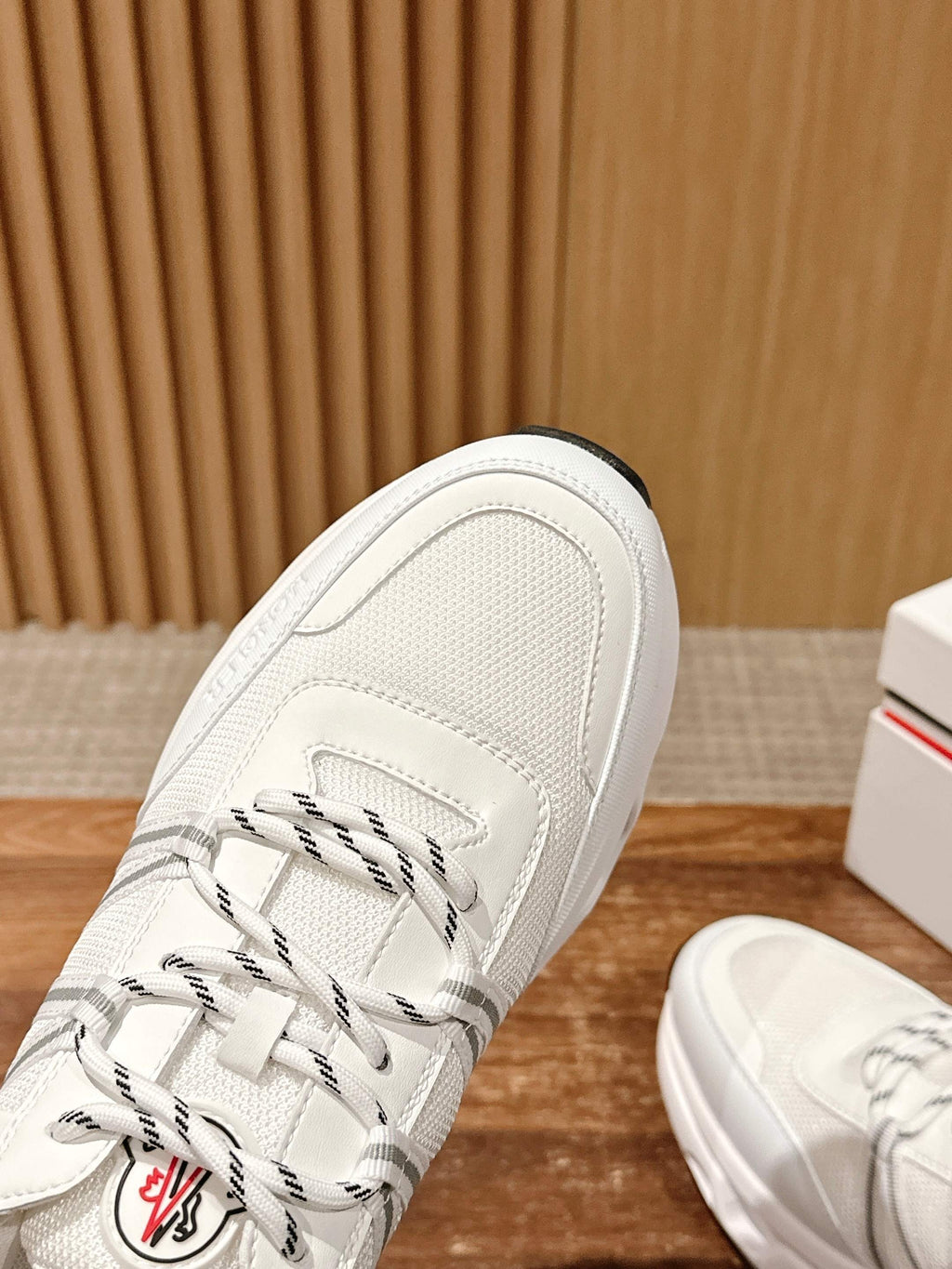 White Moncler sneaker toe with lace-up paneling and side logo embroidery detail.