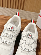 White Moncler sneakers viewed from above with lace-up stitching and red heel accents.